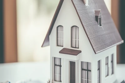 Hausmodell mit Taschenrechner – Symbolbild für die Entscheidung zwischen Privatverkauf und Makler im Allgäu